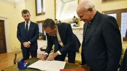 Cisco-Chef unterzeichnet die Erklärung in Rom, rechts steht Erzbischof Vincenzo Paglia