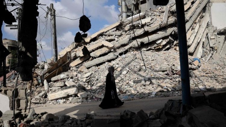 Una donna palestinese cammina tra le macerie di edifici distrutti a Rafah, nel sud della Striscia di Gaza