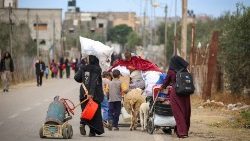Displaced Palestinians in Rafah in the southern Gaza Strip carry their belongings as they leave following a 6 May evacuation order by the Israeli army 