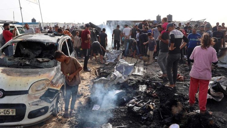 Palestinos se reúnem no local de um ataque israelense a um campo de deslocados internamente em Rafah (AFP)
