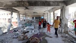 A displaced family surveys the damage done to school in the Nuseirat camp in Gaza