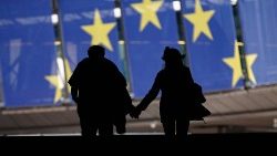 Händehaltendes Paar vor einem Banner der EU-Flagge beim EU-Parlament in Brüssel
