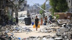 A Palestinian man carries water past destroyed buildings in Khan Yunis in the Gaza Strip