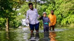 Pessoas atravessam águas inundadas após fortes chuvas em Sylhet