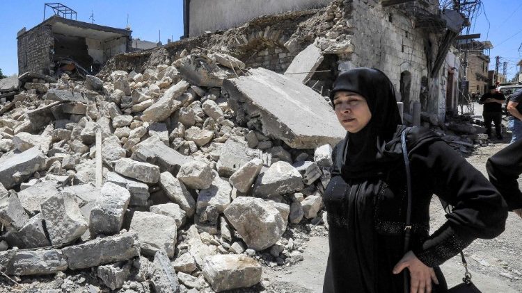 A woman walks past the rubble of a destroyed building in Yaroun, Lebanon