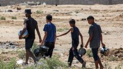 Palestinians northwest of Rafah walk to collect food from a charity kitchen