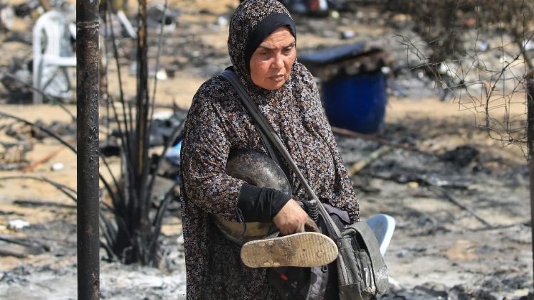Mulher com itens recuperados após ataque israelense na Faixa de Gaza, em 29 de junho de 2024