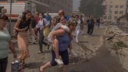 Uma mulher carrega uma menina ao lado de um prédio fortemente danificado do Hospital Infantil Ohmatdyt após um ataque com mísseis russos em Kiev, em 8 de julho de 2024. (Roman Pilipey)