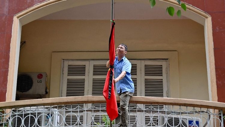 A man secures the Vietnamese national flag at half-mast and tied with a black ribbon following the death of Vietnam's former President Nguyen Phu Trong