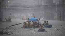 Des sauveteurs pagaient sur leurs bateaux le long d'une rue inondée à Manille le 24 juillet 2024 lors de fortes pluies provoquées par le typhon Gaemi.