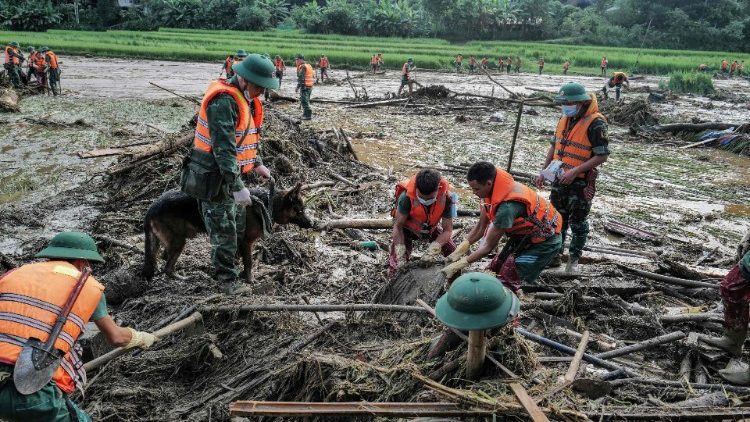 Rescue workers dig through debris at the site of a landslide in Vietnam's Lao Cai province