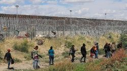 Migrants arrive near the US border wall in Mexico