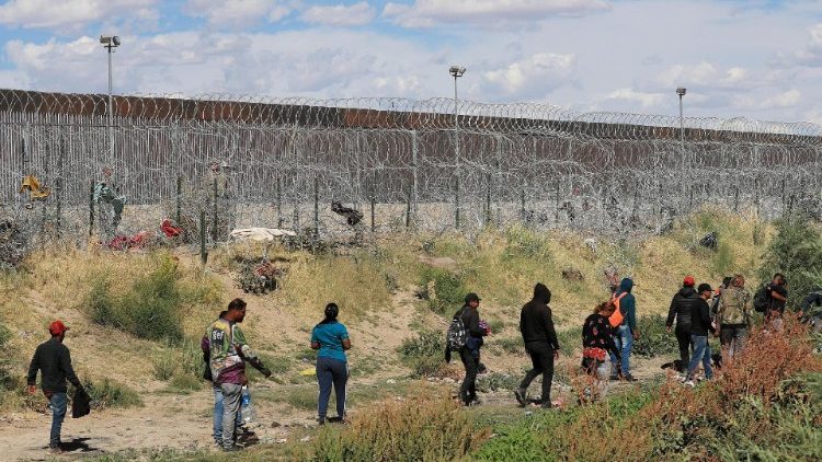 Migrants arrive near the US border wall in Mexico