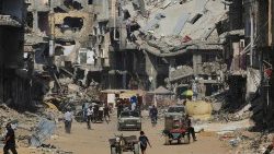 Palästinenser bahnen sich ihren Weg zwischen zerstörten Gebäuden in Khan Yunis