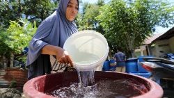 Frau schöpft sauberes Wasser, in Indonesien