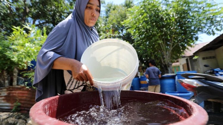 Frau schöpft sauberes Wasser, in Indonesien