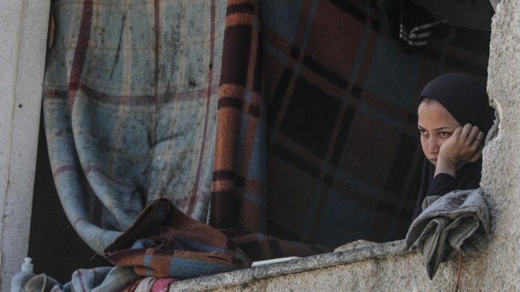 Una mujer palestina se asoma a la ventana de un edificio en ruinas