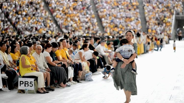 Una madre sostiene en brazos a su hijo durante la Santa Misa del Papa Francisco en Singapur.