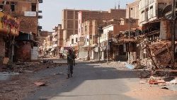Um membro das Forças Armadas Sudanesas caminha entre edifícios danificados, em Omdurman