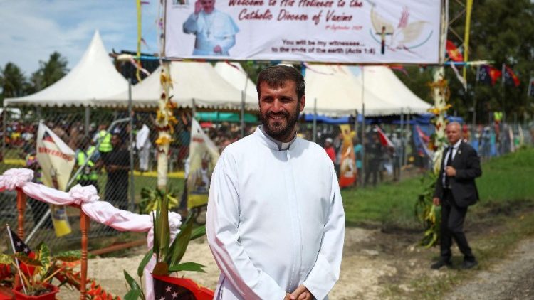 Argentinian Father Martin Prado, IVE, stands in front of a banner welcoming Pope Francis