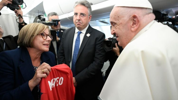 Pope Francis greeting journalists aboard the papal flight to Jakarta