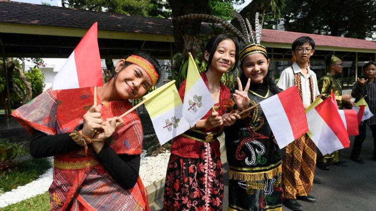 Children waving Vatican and Indonesian flags welcome the Pope