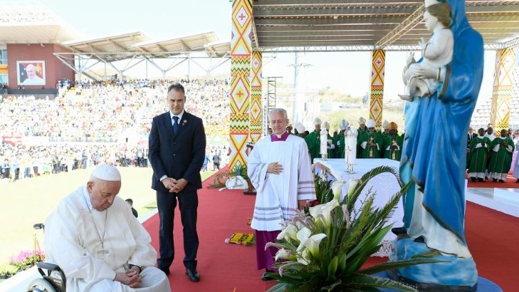 Pope Francis prays before a statue of Mary after Mass