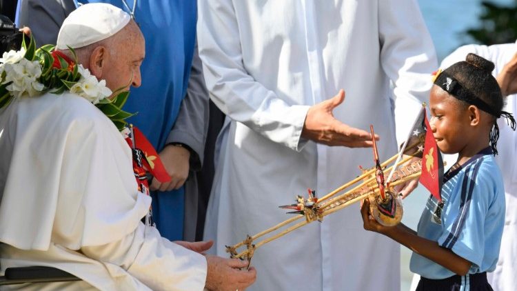 Franziskus, mit Blumenkranz, empfängt ein Geschenk von einem Mädchen