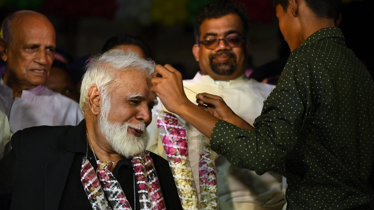 A Pakistani Christian youth garlands Pakistani Cardinal Joseph Coutts (L) at Saint Patrick Church in Karachi on July 10, 2018. (Photo by ASIF HASSAN / AFP)