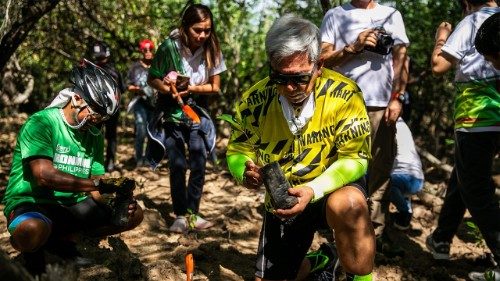 Bishop Jose Colin Bagaforo (yellow shirt), president of Caritas Philippines, leads the planting of mangrove trees during the 2nd Bike for Kalikasan (environment) event in Lobo town, Philippines. Photo by Mark Saludes