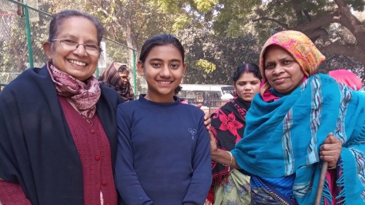 Ir. Shalini com dois membros de uma família que estão alojados em barracão temporário à beira da estrada