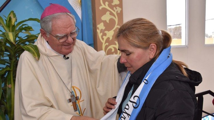 Monsignor Oscar Ojea consegna una fascia con i colori della bandiera argentina ad una delle cuoche delle mense comunitarie per i poveri, come simbolo di unità e fraternità