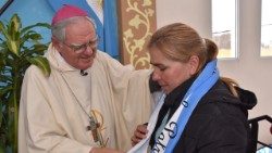 Monseñor Oscar Ojea, Presidente de la Conferencia Episcopal Argentina, entrega a una de las "Madres de la Patria" una banda con los colores de la bandera argentina, como símbolo de unidad y hermandad.