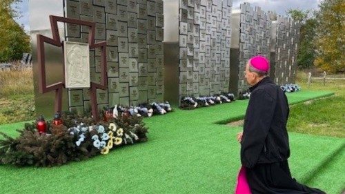 Archbishop William Lori kneels at the cemetery in Bucha, Ukraine