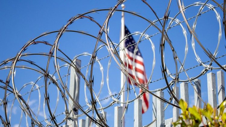 An American flag flies behind razor wire