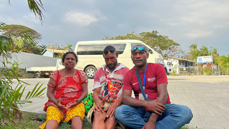 From left: Anna Dinz, Christopher Kenneth and John Junior Dinz, sit outside Saint John the Apostle Catholic Church, after making a two-day trip from Mount Hagen to Port Moresby for Pope Francis’ Apostolic Journey