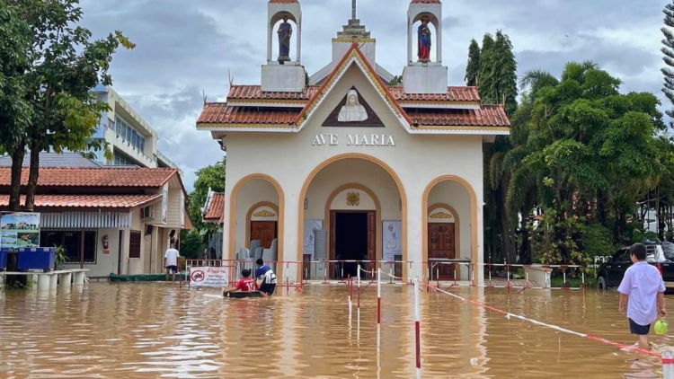 people are walking through a flooded street in front of a church