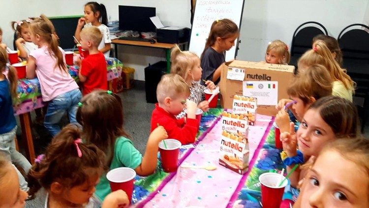 Les enfants goûtant aux biscuits et bonbons envoyés de Rome.